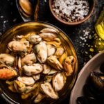 Pickled mussels in a glass bowl with spices.