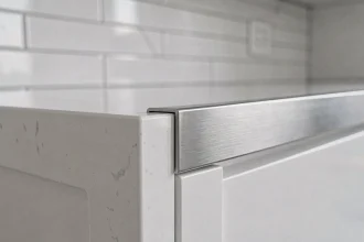 Profil en L inox brossé fixé sur le bord d'un plan de travail en quartz blanc dans une cuisine moderne